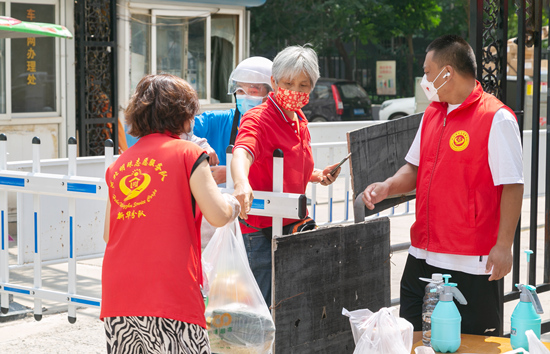 志愿者在社区门口接送快递。石家庄市文明办供图